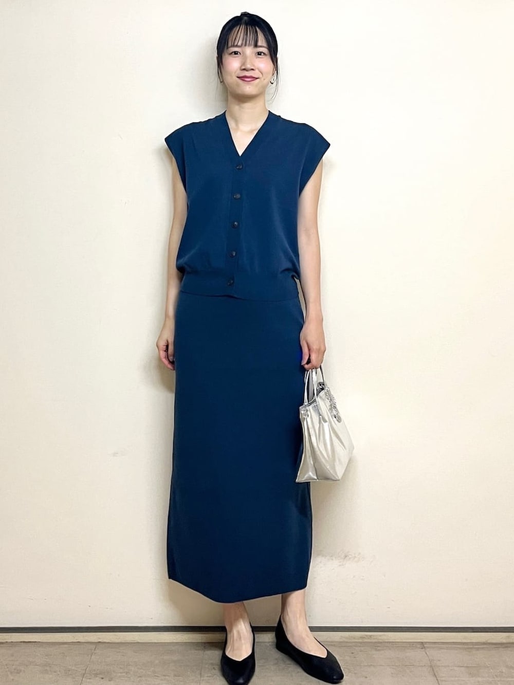 ブルー系のベスト、ブルー系のスカート、シルバー系のトートバッグを着用したレディースの夏コーディネートの2枚目の写真