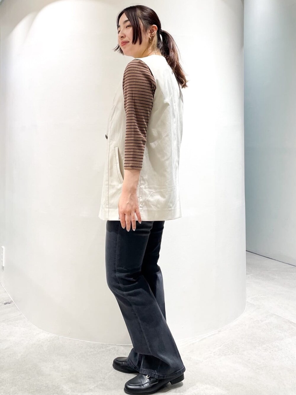 ブラック系のドレスシューズ、ブラック系のデニムパンツ、ホワイト系のベストを着用したレディースの夏コーディネートの5枚目の写真