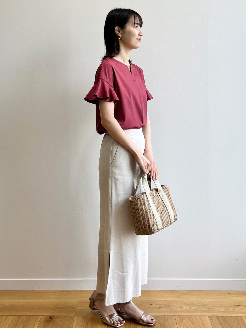 レッド系のTシャツ/カットソー、ゴールド系のサンダル、ベージュ系のスカートを着用したレディースの春コーディネートの2枚目の写真