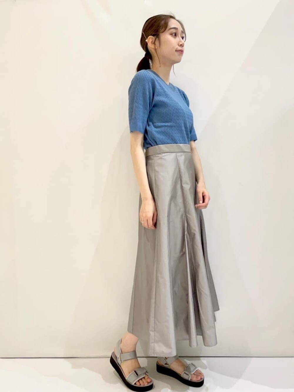 ブルー系のニット/セーター、グレー系のスカート、グレー系のサンダルを着用したレディースの夏コーディネートの3枚目の写真