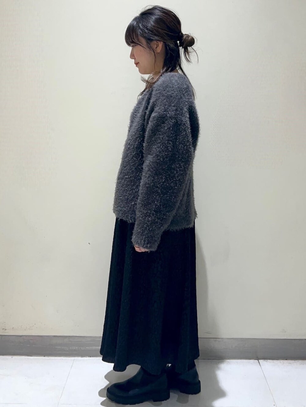 ブラック系のスカート、ブラック系のブーツ、グレー系のカーディガン/ボレロを着用したレディースの秋コーディネートの2枚目の写真