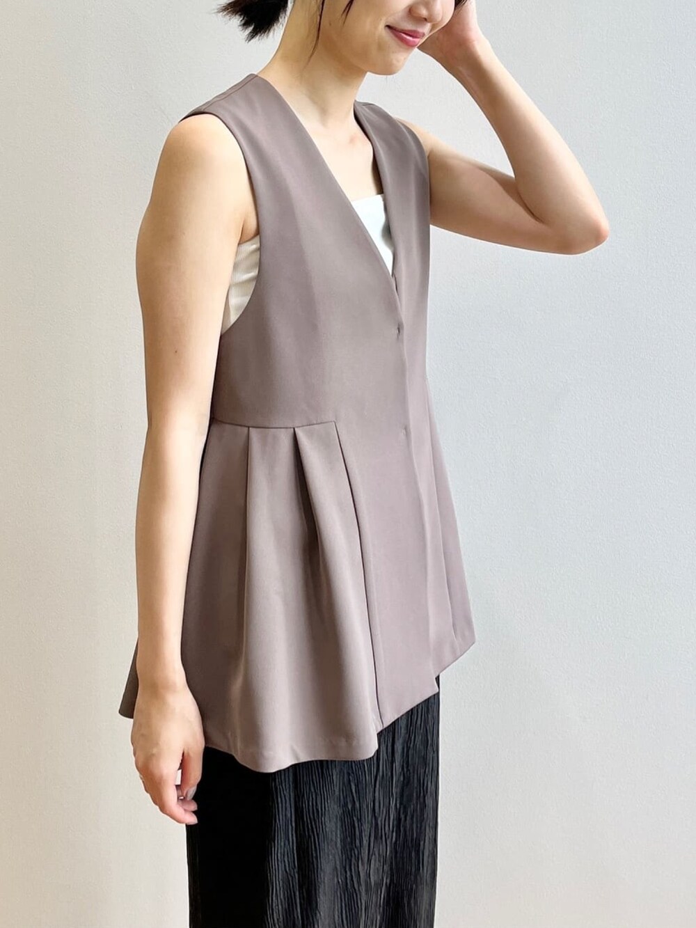 ホワイト系のタンクトップ、ホワイト系のサンダル、ブラウン系のベストを着用したレディースの夏コーディネートの6枚目の写真