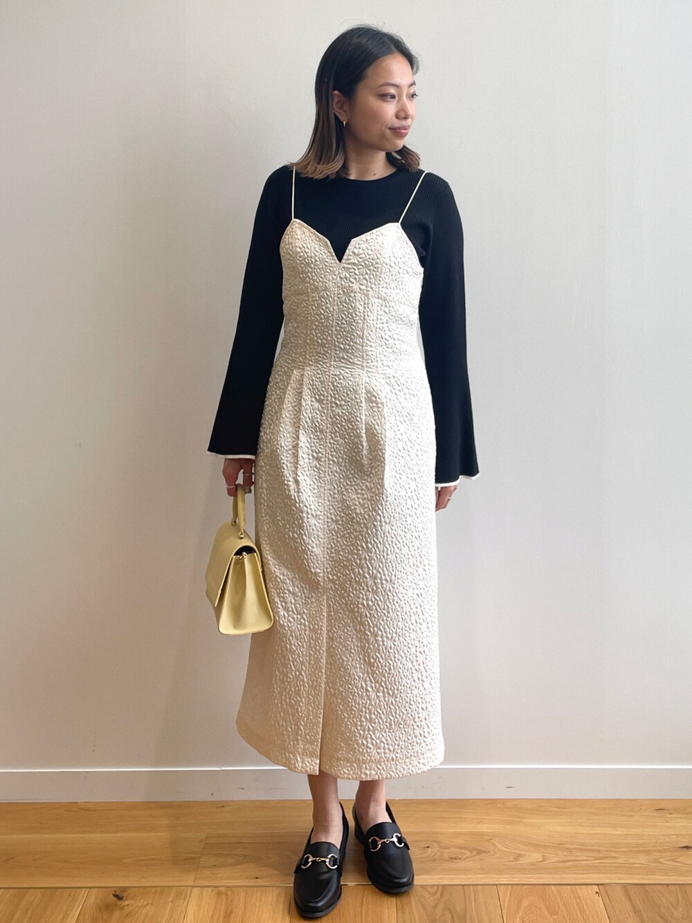 ベージュ系のトレンチコート、ホワイト系のワンピース、イエロー系のショルダーバッグを着用したレディースの春コーディネートの4枚目の写真