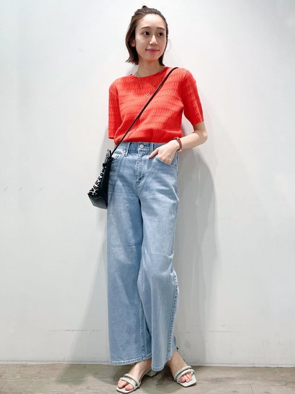 オレンジ系のニット/セーター、ブルー系のデニムパンツ、グリーン系のサンダルを着用したレディースの春コーディネートの4枚目の写真