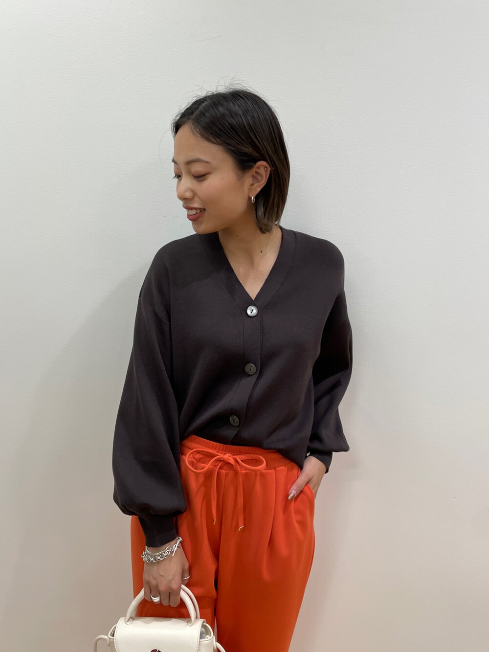 ブラウン系のカーディガン/ボレロ、オレンジ系のその他パンツ、ホワイト系のショルダーバッグを着用したレディースの秋コーディネートの3枚目の写真