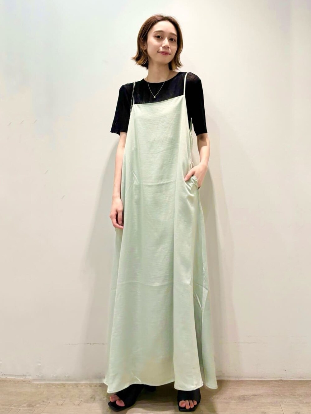 ブラック系のニット/セーター、グリーン系のワンピース、シルバー系のショルダーバッグを着用したレディースの夏コーディネートの3枚目の写真