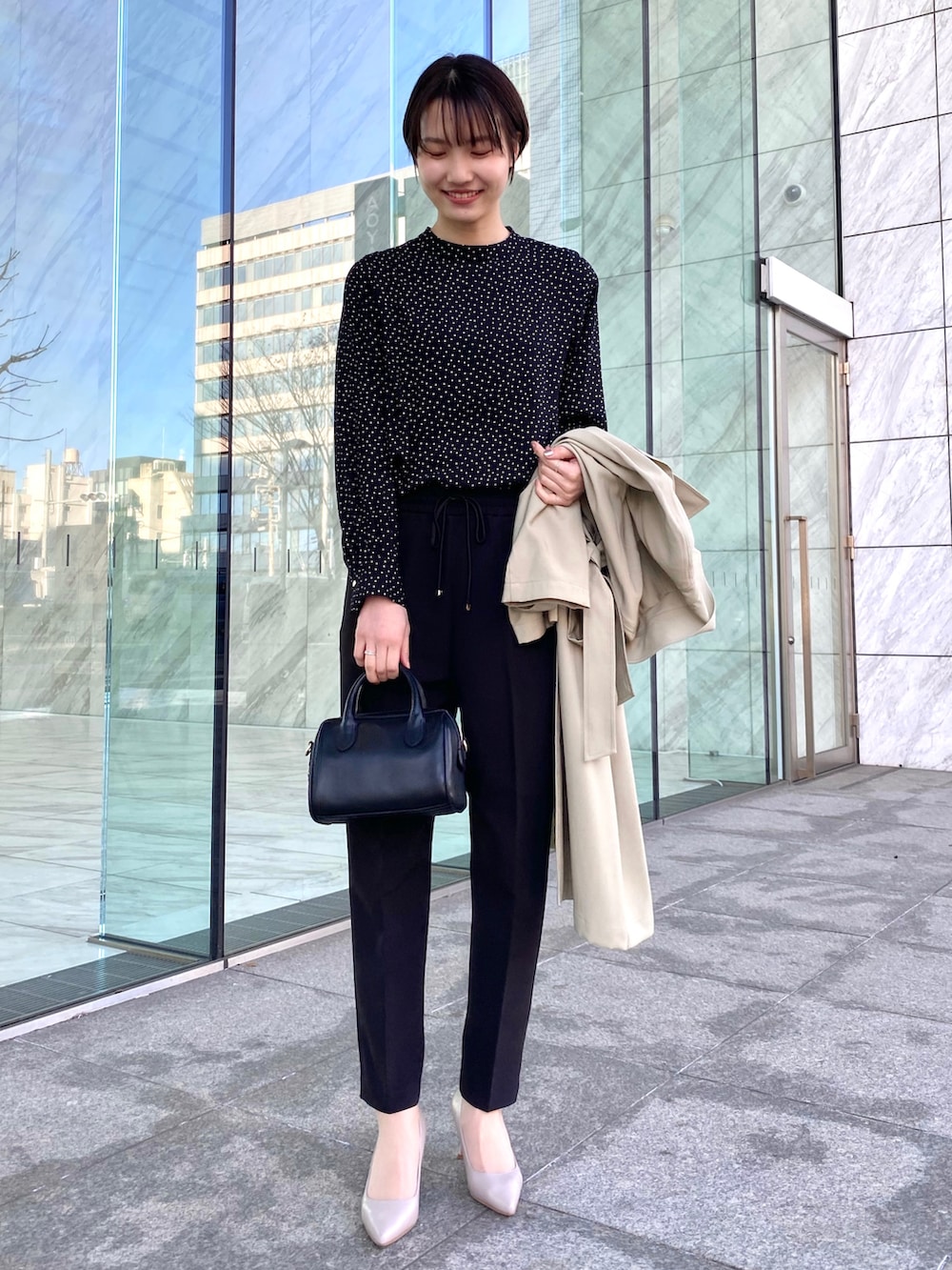 ベージュ系のトレンチコート、ブラック系のショルダーバッグ、ブラック系のその他パンツを着用したレディースの春コーディネートの2枚目の写真