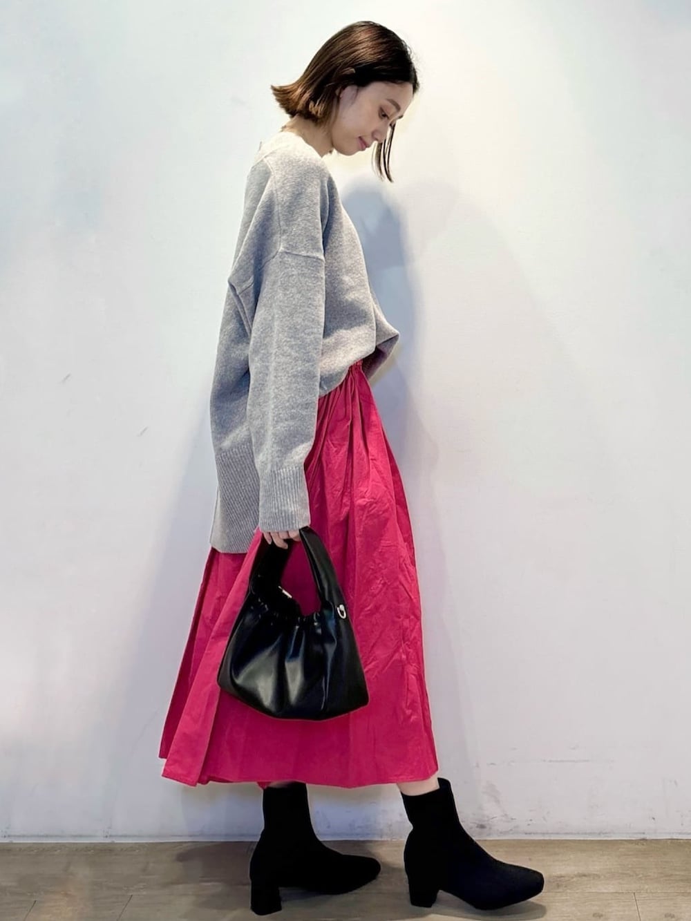 グレー系のニット/セーター、ピンク系のスカート、ブラック系のショルダーバッグを着用したレディースの冬コーディネートの3枚目の写真