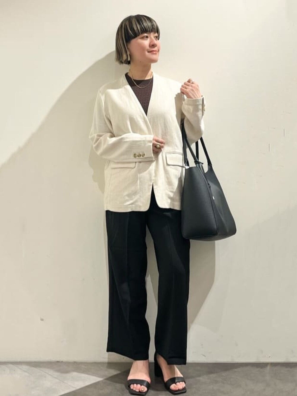 ベージュ系のノーカラージャケット、ブラウン系のニット/セーター、ブラック系のトートバッグを着用したレディースの春コーディネートの3枚目の写真