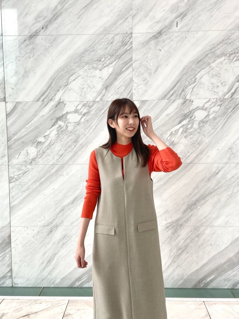 オレンジ系のニット/セーター、ベージュ系のワンピース、ホワイト系のブーツを着用したレディースの秋コーディネートの7枚目の写真