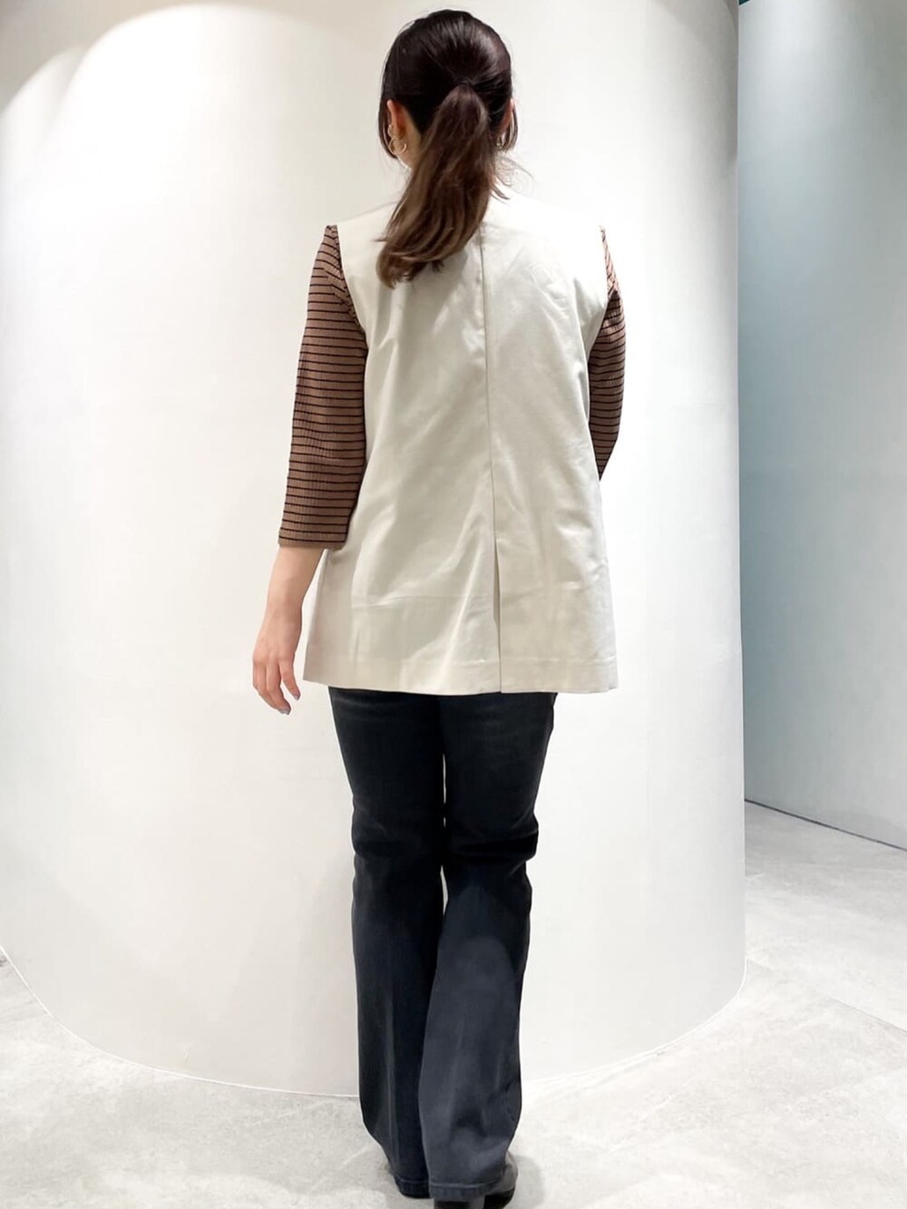 ブラック系のドレスシューズ、ブラック系のデニムパンツ、ホワイト系のベストを着用したレディースの夏コーディネートの6枚目の写真