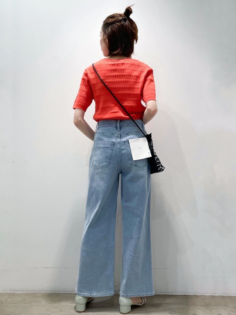 オレンジ系のニット/セーター、ブルー系のデニムパンツ、グリーン系のサンダルを着用したレディースの春コーディネートの2枚目の写真