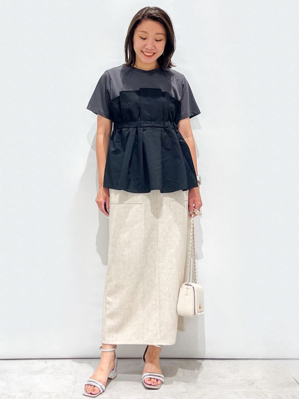 ブラック系のTシャツ/カットソー、ベージュ系のスカート、ホワイト系のショルダーバッグを着用したレディースの夏コーディネートの2枚目の写真