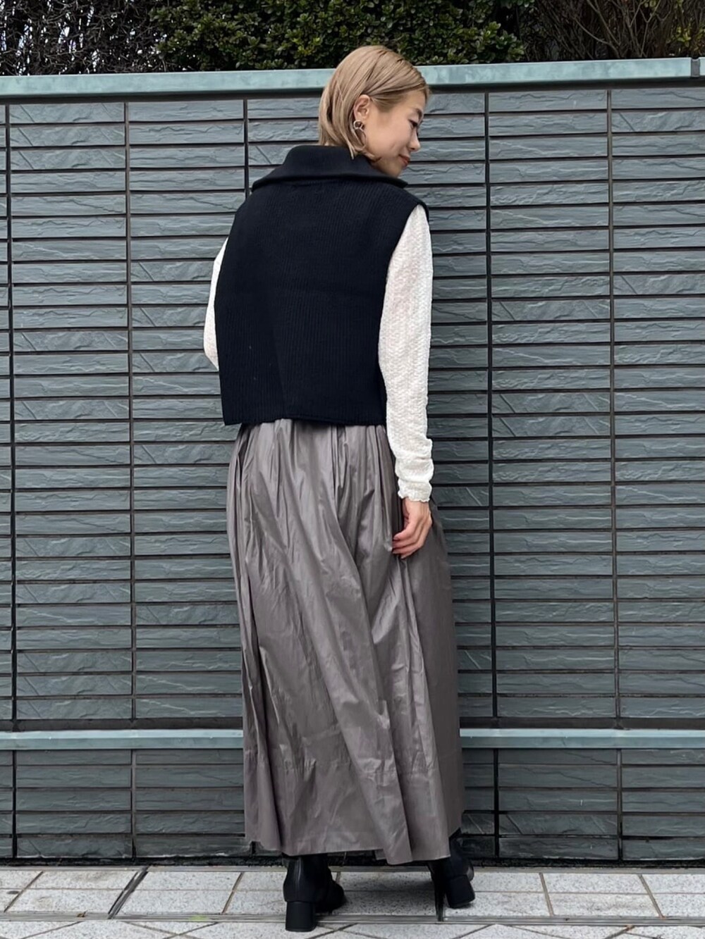 ブラック系のニット/セーター、ホワイト系のTシャツ/カットソー、グリーン系のスカートを着用したレディースの秋コーディネートの4枚目の写真