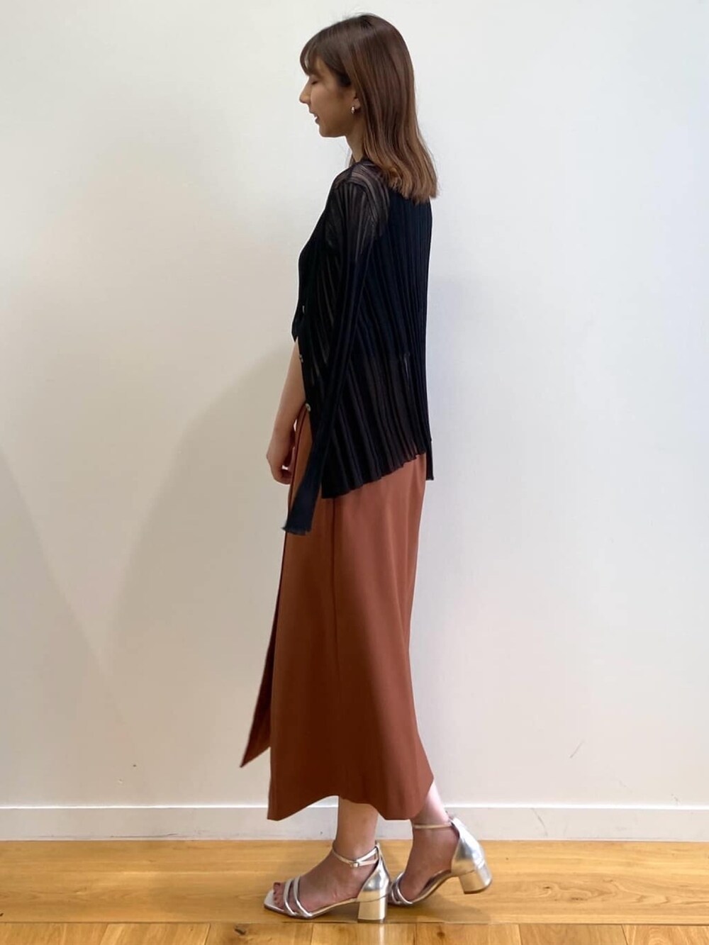 ブラウン系のスカート、シルバー系のサンダル、ブラック系のニット/セーターを着用したレディースの春コーディネートの4枚目の写真