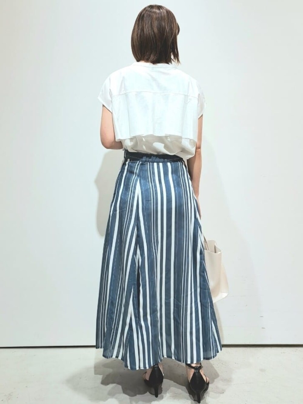 ホワイト系のTシャツ/カットソー、ブルー系のスカート、ブラック系のトートバッグを着用したレディースの春コーディネートの2枚目の写真