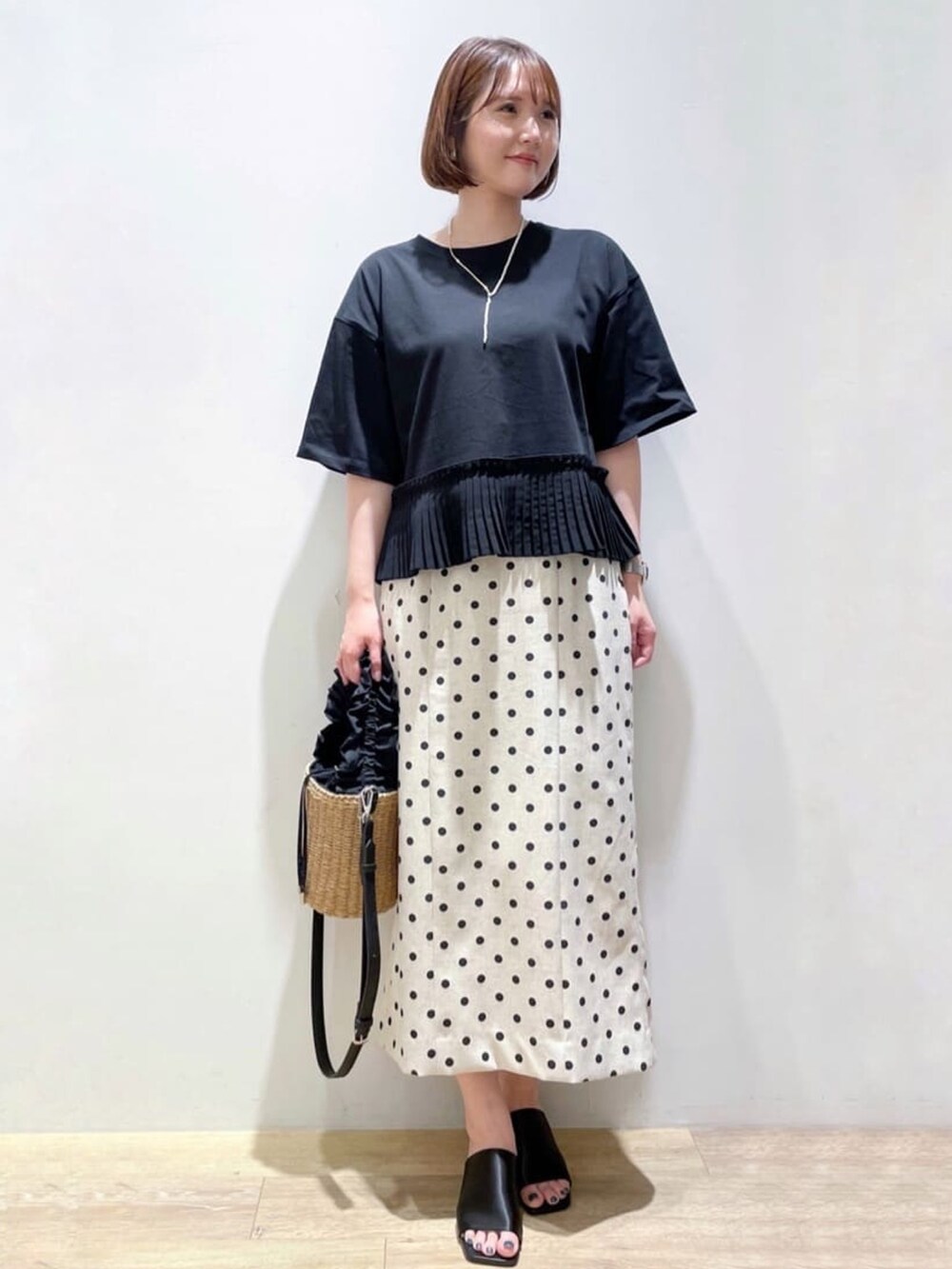 ベージュ系のスカート、ブラック系のTシャツ/カットソー、ブラック系のサンダルを着用したレディースの夏コーディネートの3枚目の写真