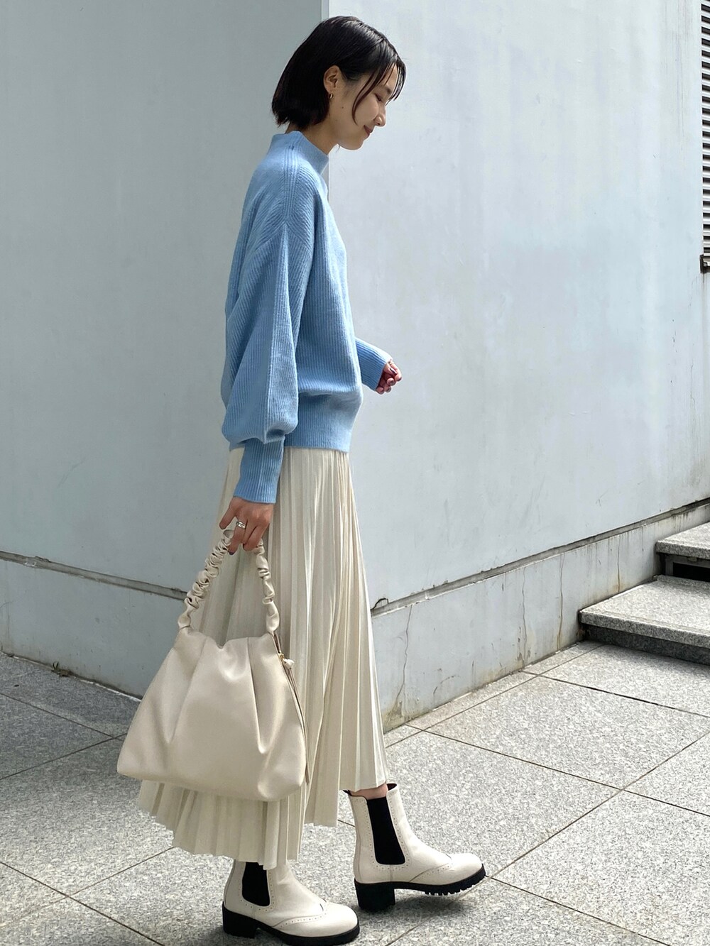 ブルー系のニット/セーター、ホワイト系のスカート、ホワイト系のハンドバッグを着用したレディースの秋コーディネートの2枚目の写真