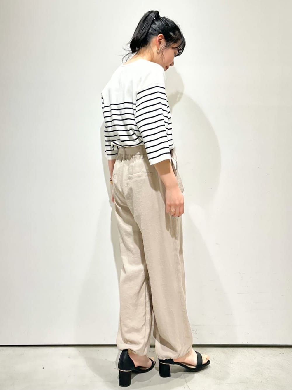 ベージュ系のその他パンツ、ブラック系のサンダル、ホワイト系のニット/セーターを着用したレディースの春コーディネートの4枚目の写真