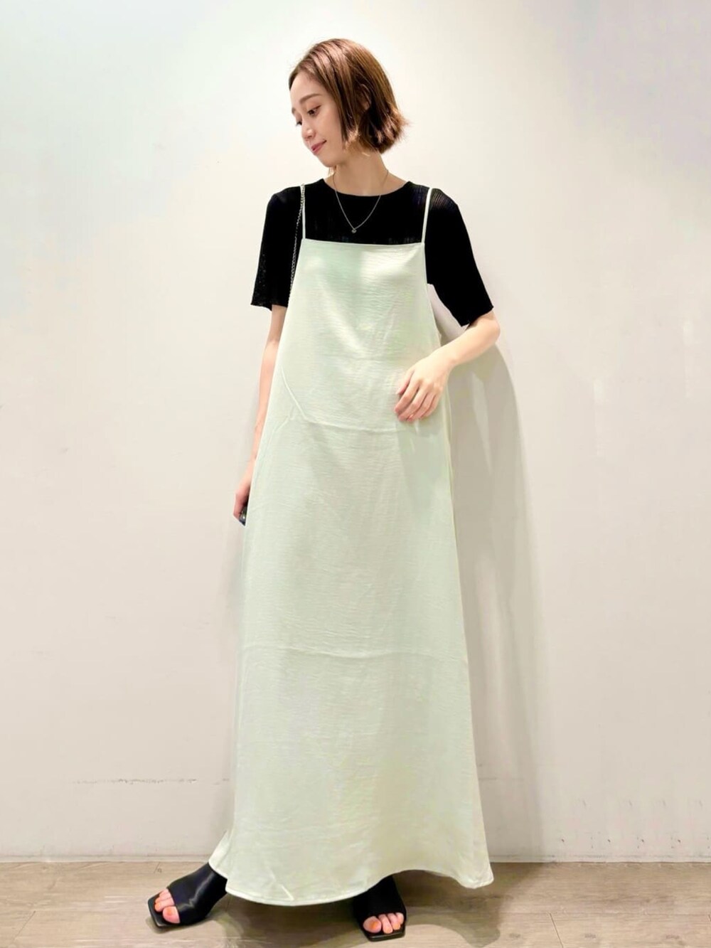 ブラック系のニット/セーター、グリーン系のワンピース、シルバー系のショルダーバッグを着用したレディースの夏コーディネートの2枚目の写真