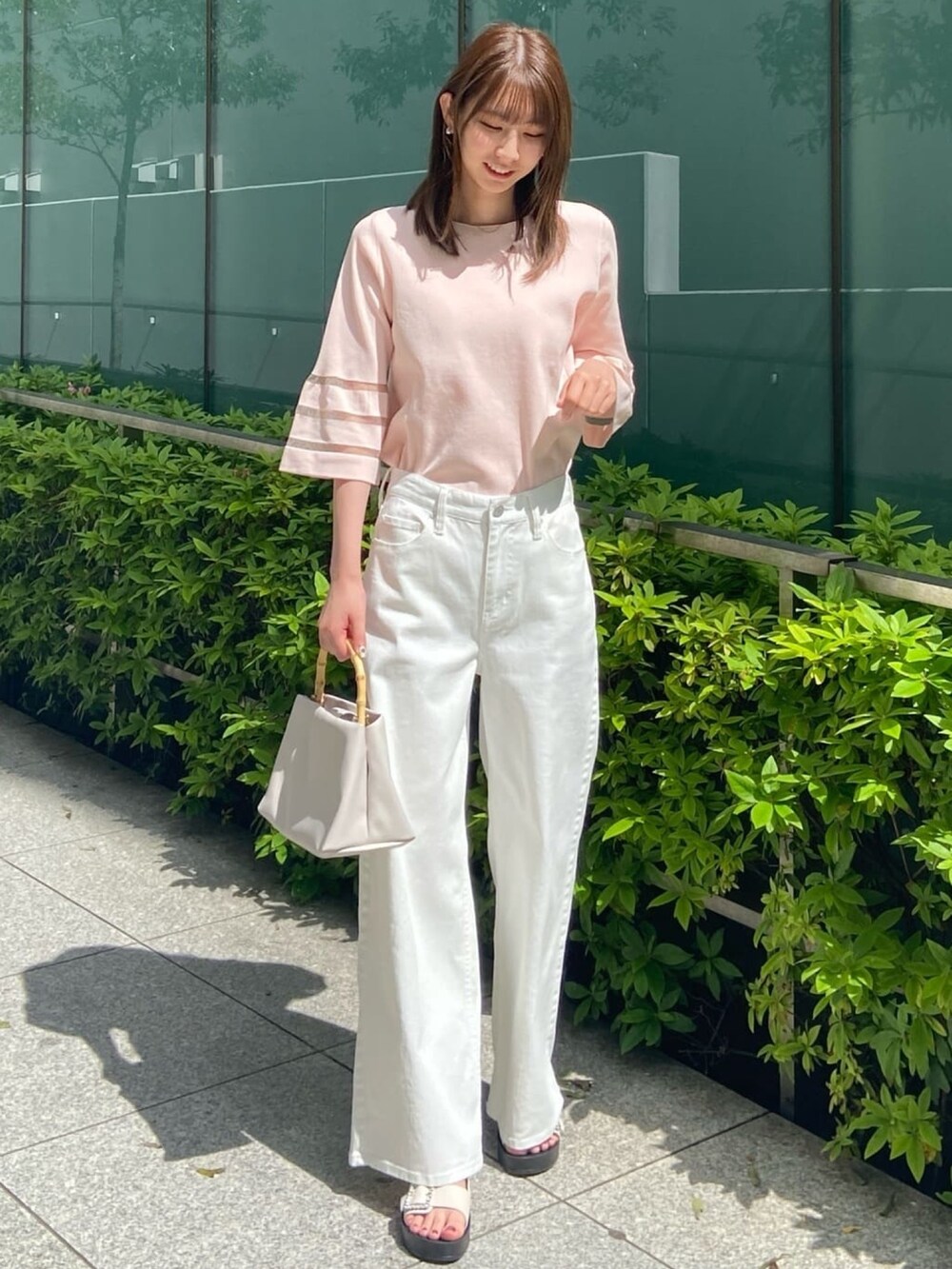 ピンク系のニット/セーター、ホワイト系のデニムパンツ、ホワイト系のサンダルを着用したレディースの春コーディネートの2枚目の写真