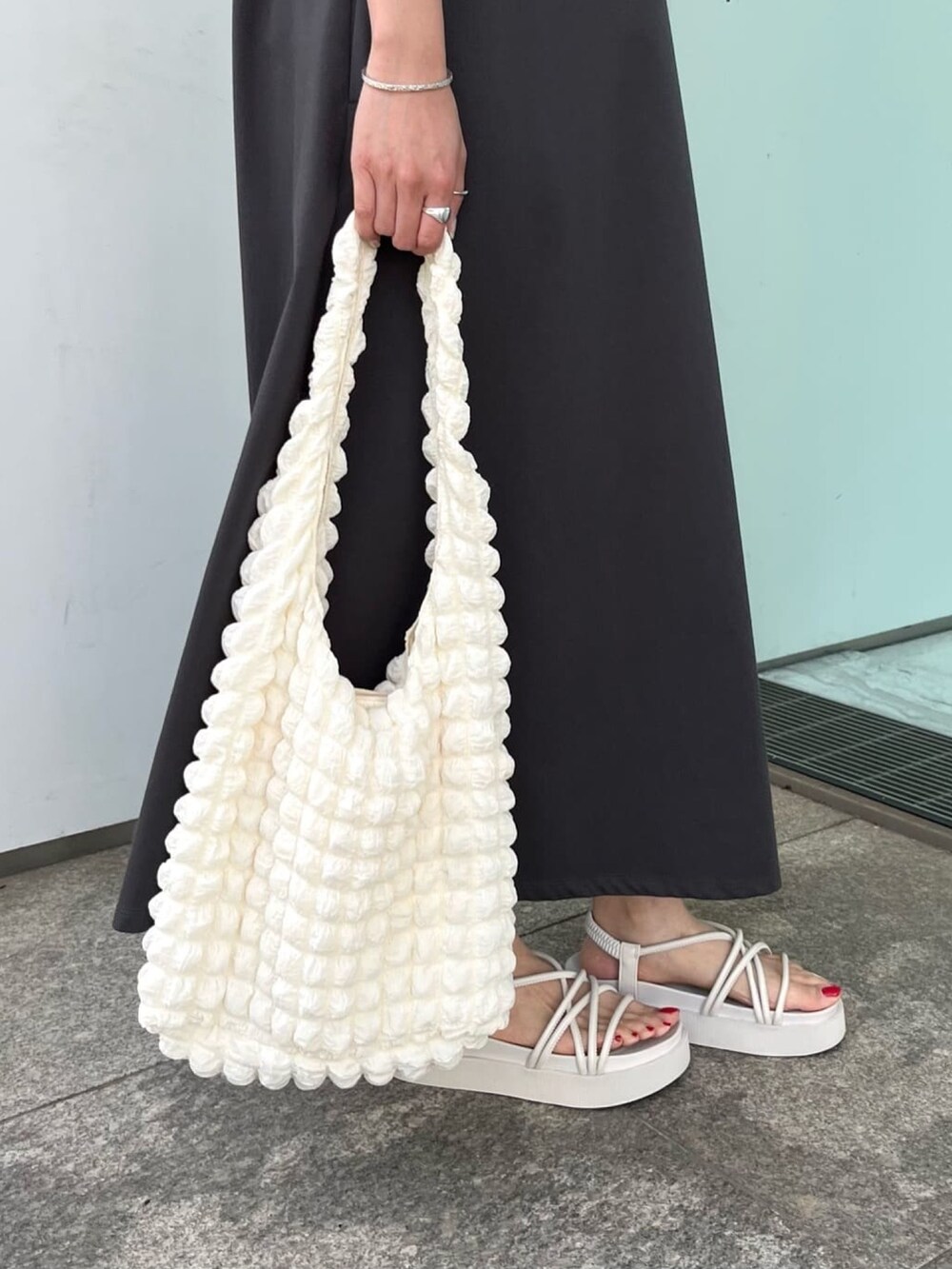 グレー系のワンピース、ホワイト系のサンダル、ホワイト系のショルダーバッグを着用したレディースの春コーディネートの4枚目の写真