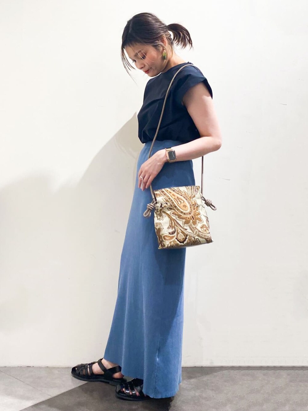 ブラック系のTシャツ/カットソー、ブルー系のスカート、ベージュ系のショルダーバッグを着用したレディースの夏コーディネートの2枚目の写真