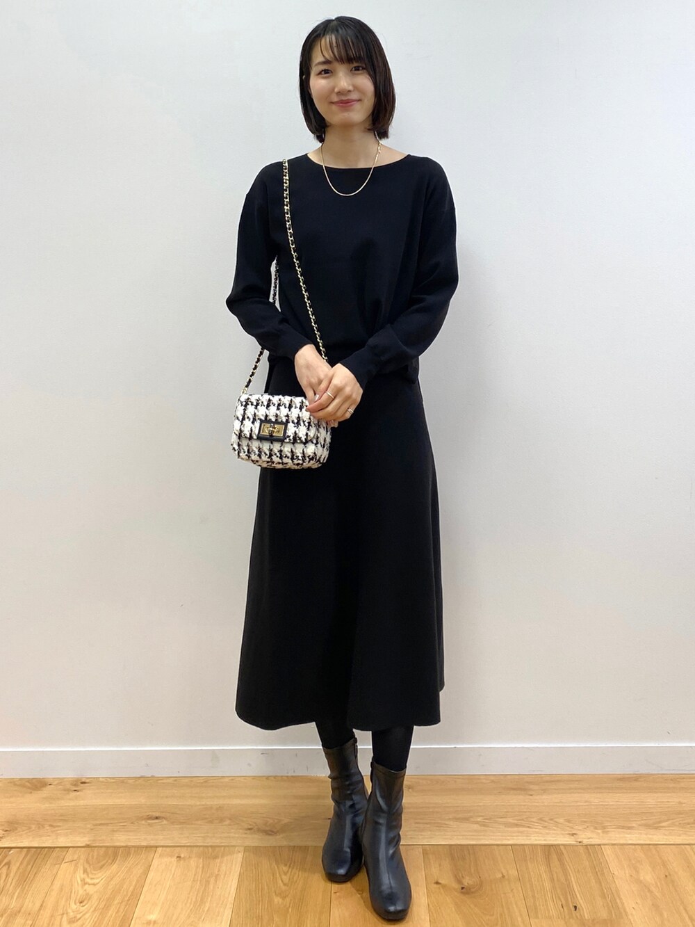 ブラック系のニット/セーター、ブラック系のスカート、ブルー系のノーカラーコートを着用したレディースの冬コーディネートの3枚目の写真