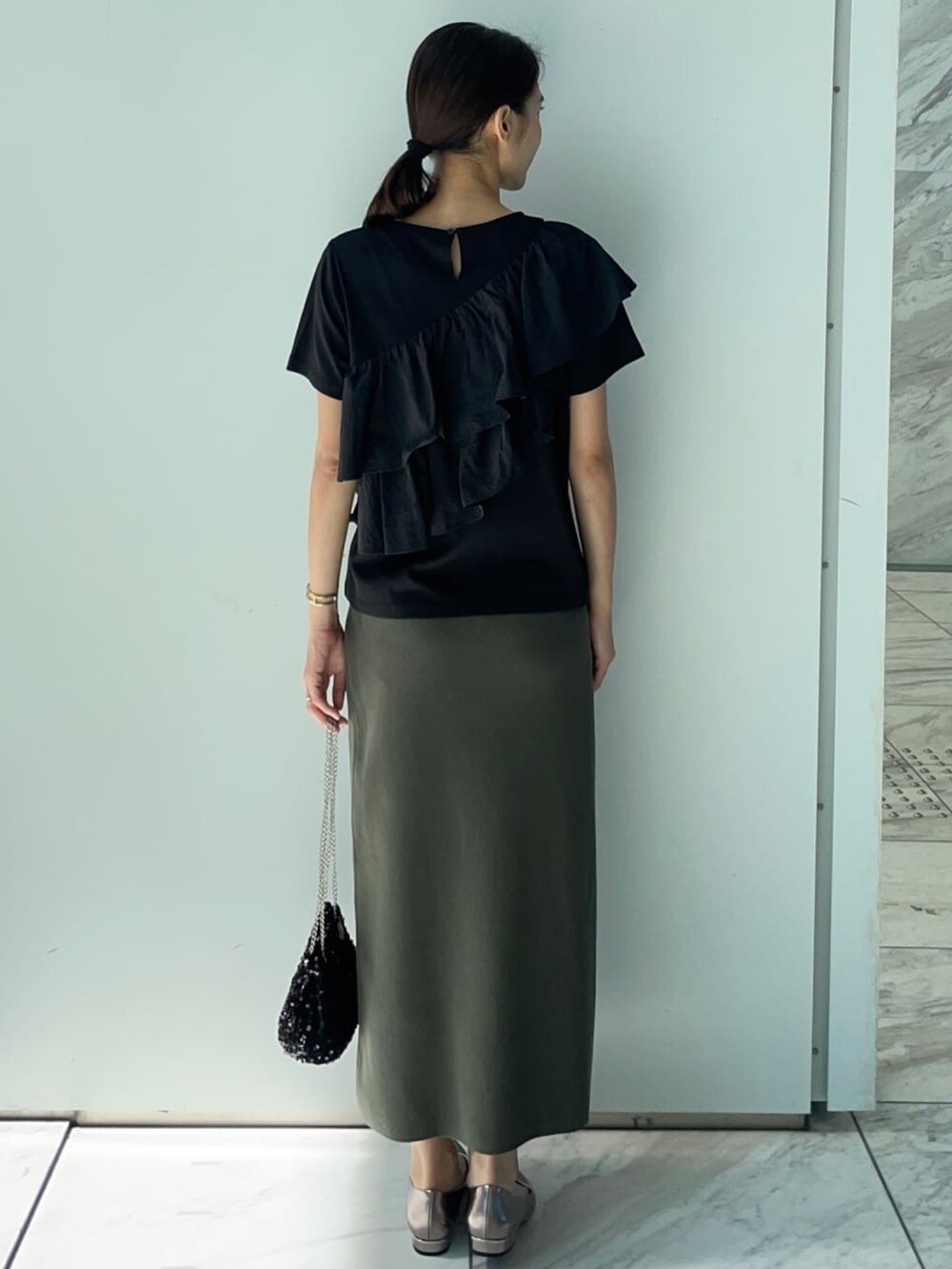 ブラック系のTシャツ/カットソー、グリーン系のスカート、シルバー系のパンプスを着用したレディースの夏コーディネートの4枚目の写真