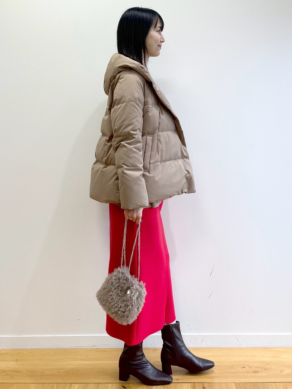 イエロー系のダウンジャケット/コート、ベージュ系のニット/セーター、レッド系のスカートを着用したレディースの秋コーディネートの5枚目の写真