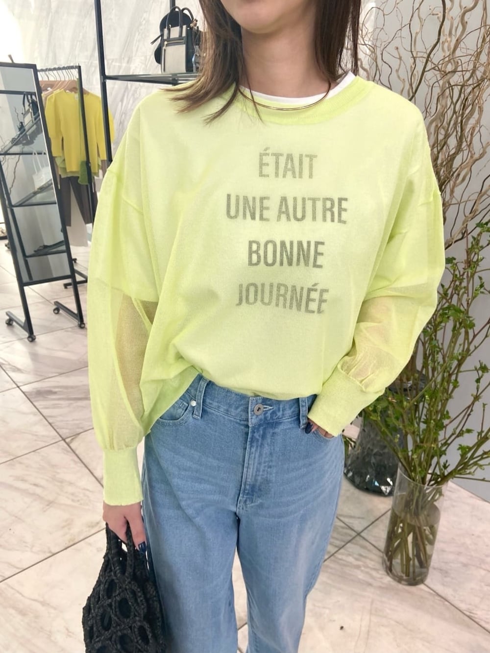 グリーン系のニット/セーター、ブルー系のデニムパンツ、ベージュ系のサンダルを着用したレディースの春コーディネートの6枚目の写真