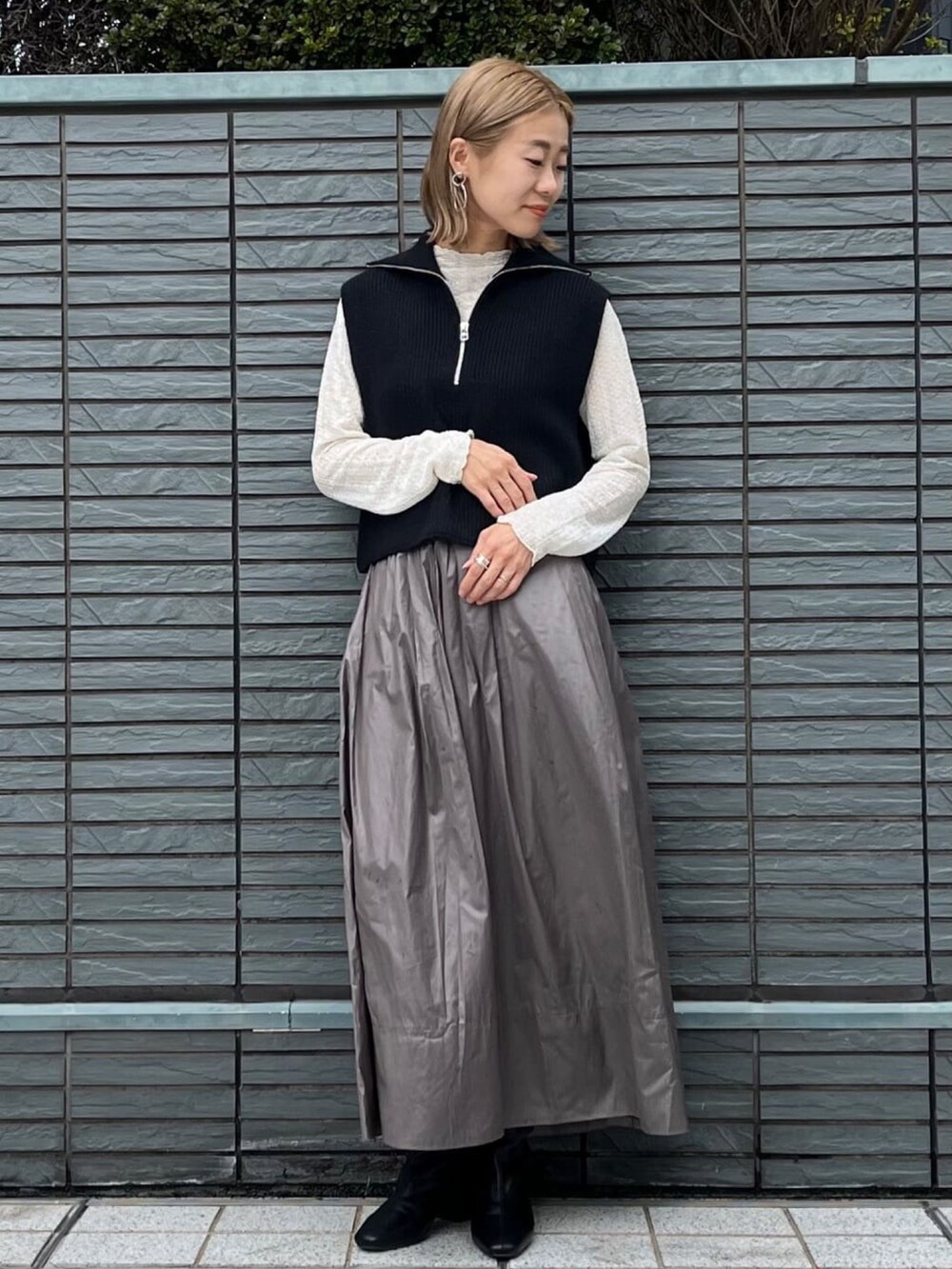 ブラック系のニット/セーター、ホワイト系のTシャツ/カットソー、グリーン系のスカートを着用したレディースの秋コーディネートの2枚目の写真