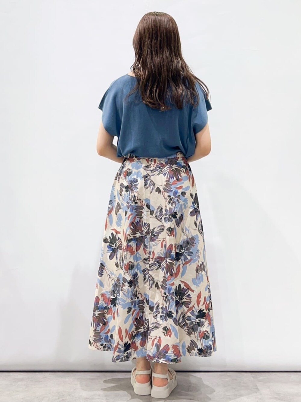 ブルー系のニット/セーター、ベージュ系のスカート、ホワイト系のサンダルを着用したレディースの夏コーディネートの3枚目の写真