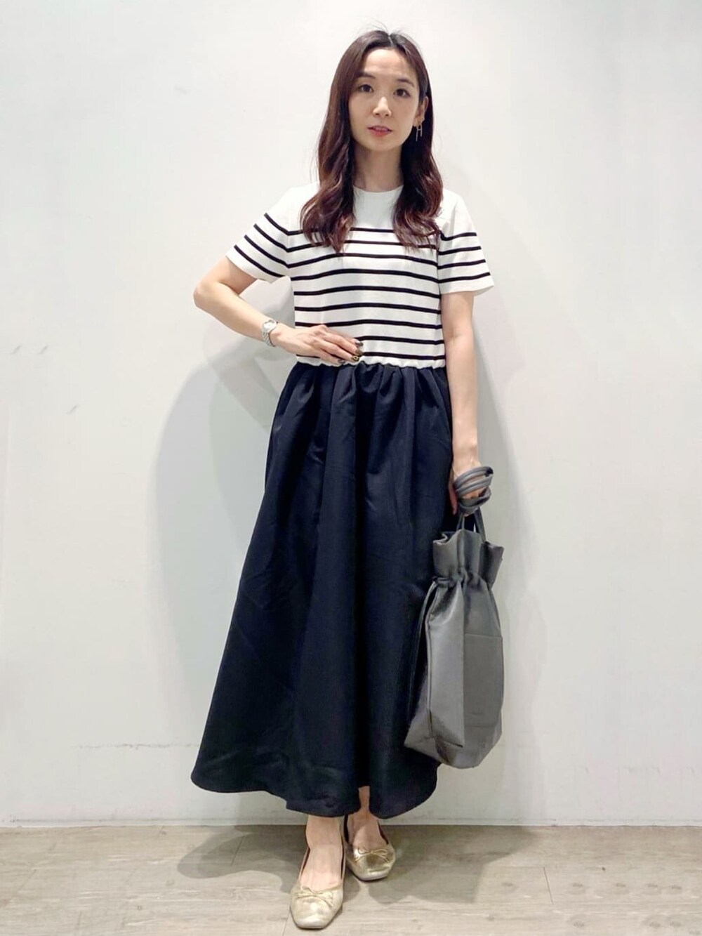 グレー系のトートバッグ、ブラック系のワンピース、ゴールド系のその他シューズを着用したレディースの夏コーディネートの4枚目の写真