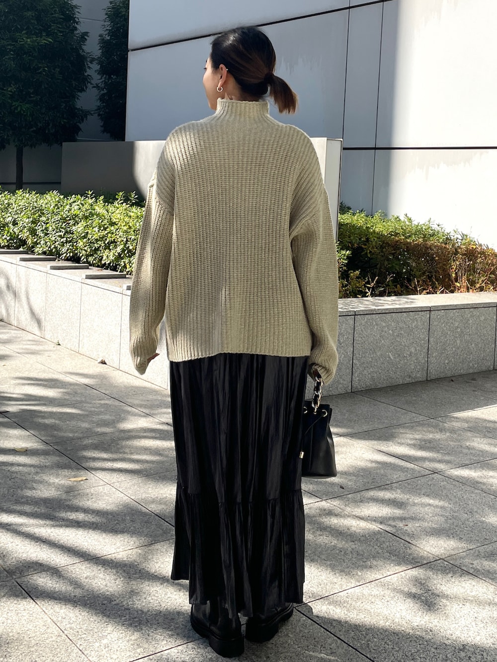 ベージュ系のニット/セーター、グレー系のスカート、ブラック系のブーツを着用したレディースの冬コーディネートの3枚目の写真