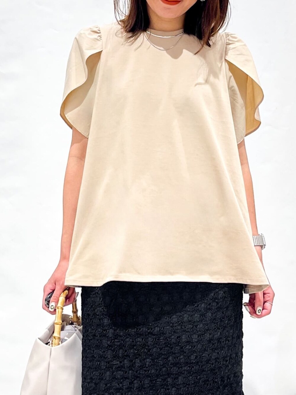 ベージュ系のTシャツ/カットソー、ブラック系のスカート、ホワイト系のショルダーバッグを着用したレディースの春コーディネートの9枚目の写真