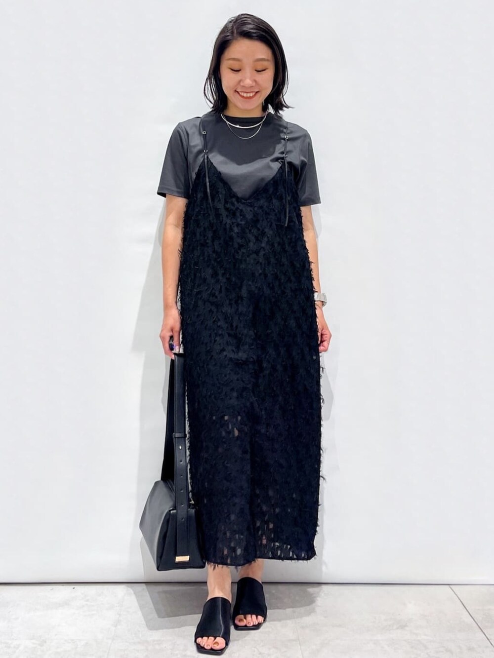 ブラック系のサンダル、ブラック系のショルダーバッグ、ブラック系のワンピースを着用したレディースの夏コーディネートの2枚目の写真