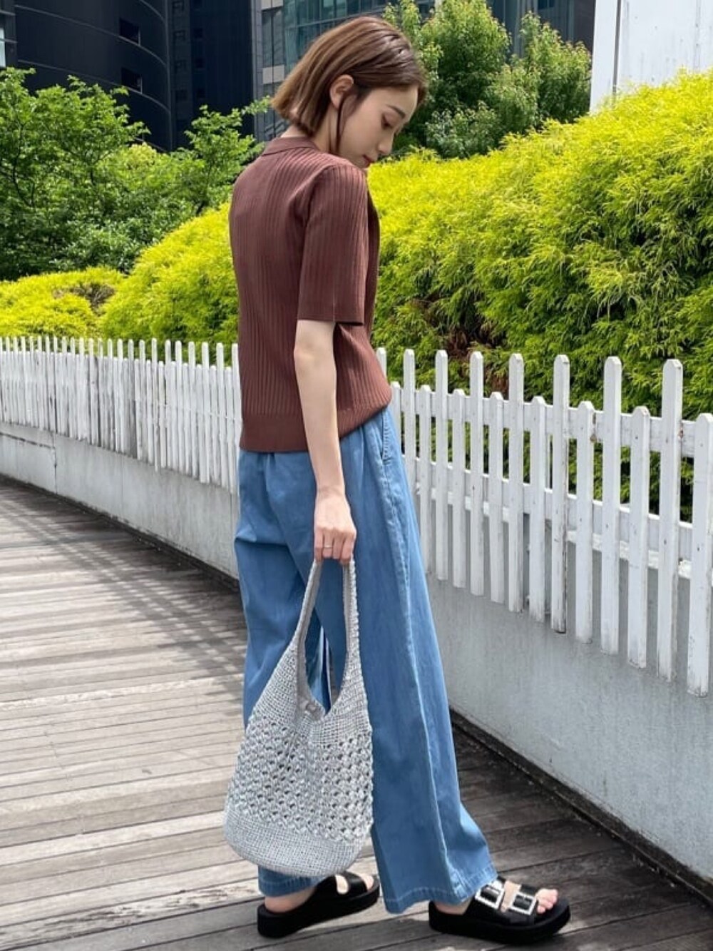 ブラウン系のニット/セーター、ブルー系のデニムパンツ、シルバー系のトートバッグを着用したレディースの春コーディネートの5枚目の写真