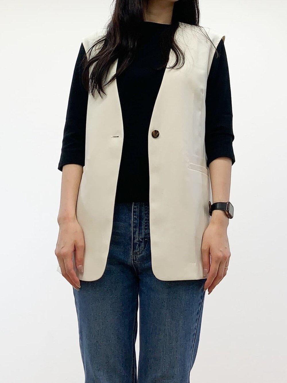 ホワイト系のベスト、ブラック系のTシャツ/カットソー、ブルー系のデニムパンツを着用したレディースの秋コーディネートの5枚目の写真