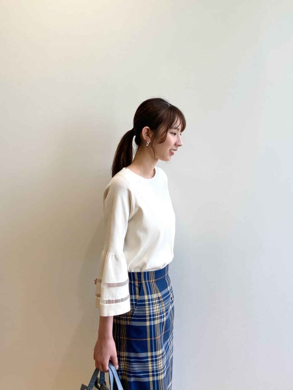 ホワイト系のニット/セーター、ブルー系のスカート、ベージュ系のパンプスを着用したレディースの夏コーディネートの9枚目の写真