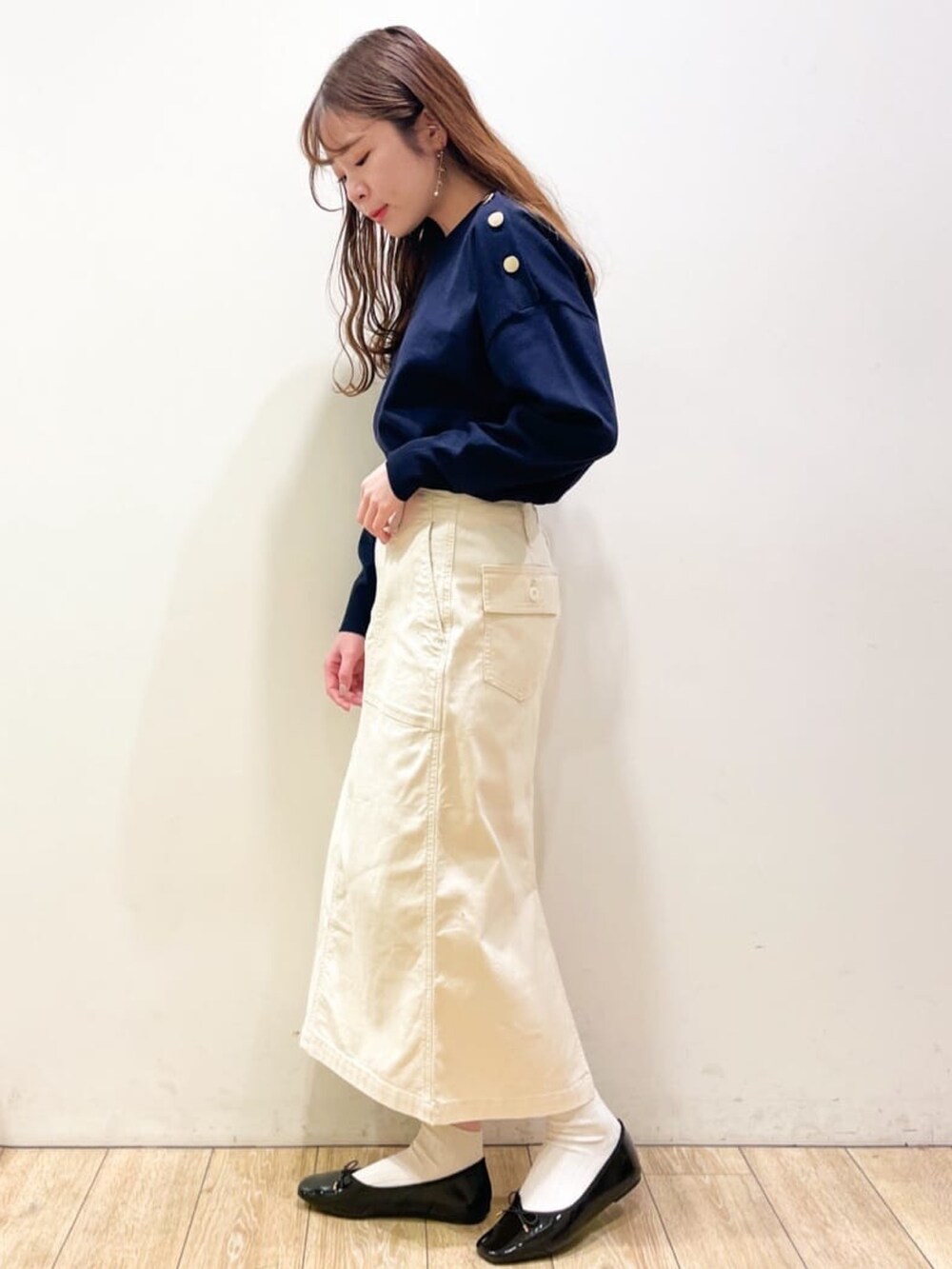 ブルー系のニット/セーター、ホワイト系のスカート、ブラック系のショルダーバッグを着用したレディースの冬コーディネートの2枚目の写真