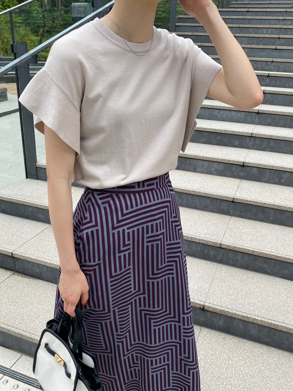ベージュ系のニット/セーター、ブルー系のスカート、ブラック系のトートバッグを着用したレディースの夏コーディネートの3枚目の写真