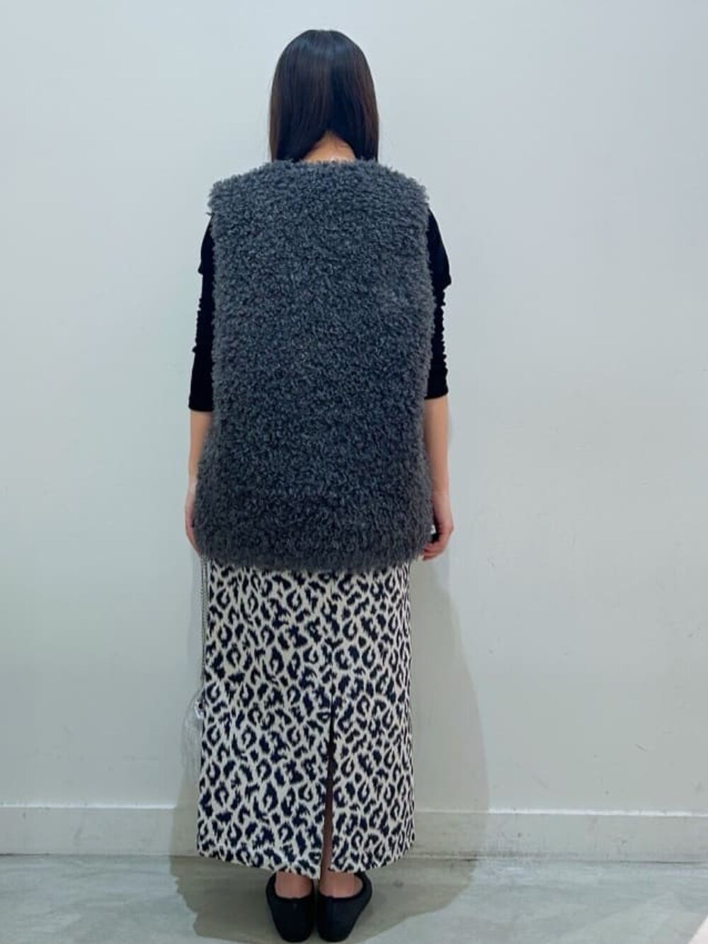 グレー系のベスト、ブルー系のスカート、ブラック系のTシャツ/カットソーを着用したレディースの秋コーディネートの3枚目の写真