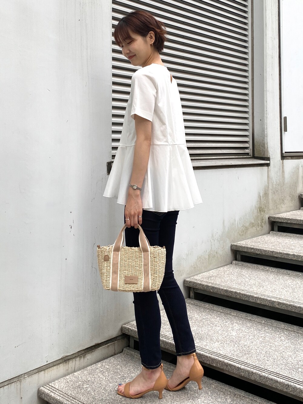 ホワイト系のTシャツ/カットソー、ブルー系のデニムパンツ、ベージュ系のトートバッグを着用したレディースの夏コーディネートの2枚目の写真