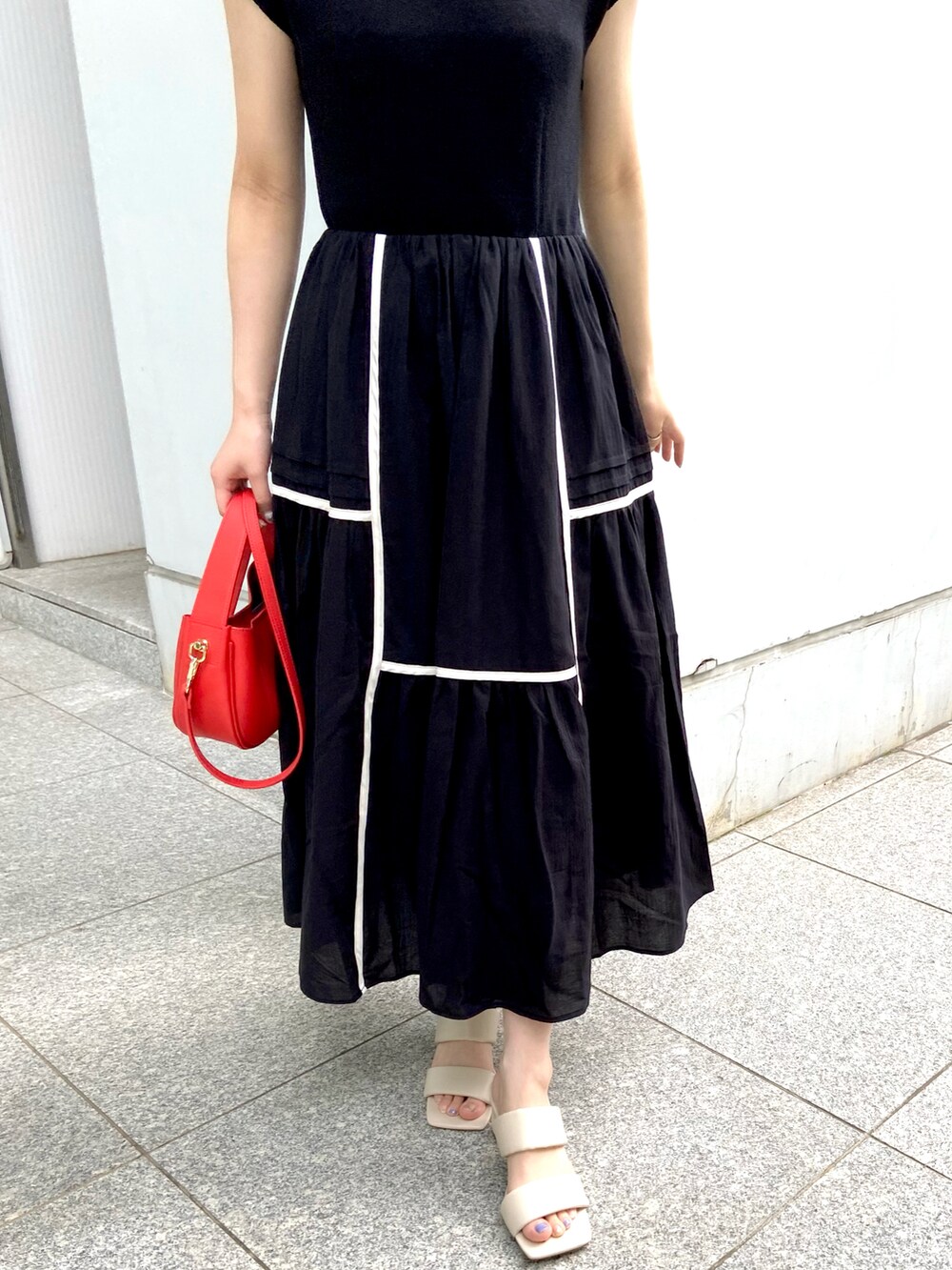 ブラック系のワンピース、レッド系のショルダーバッグ、ホワイト系のサンダルを着用したレディースの夏コーディネートの2枚目の写真
