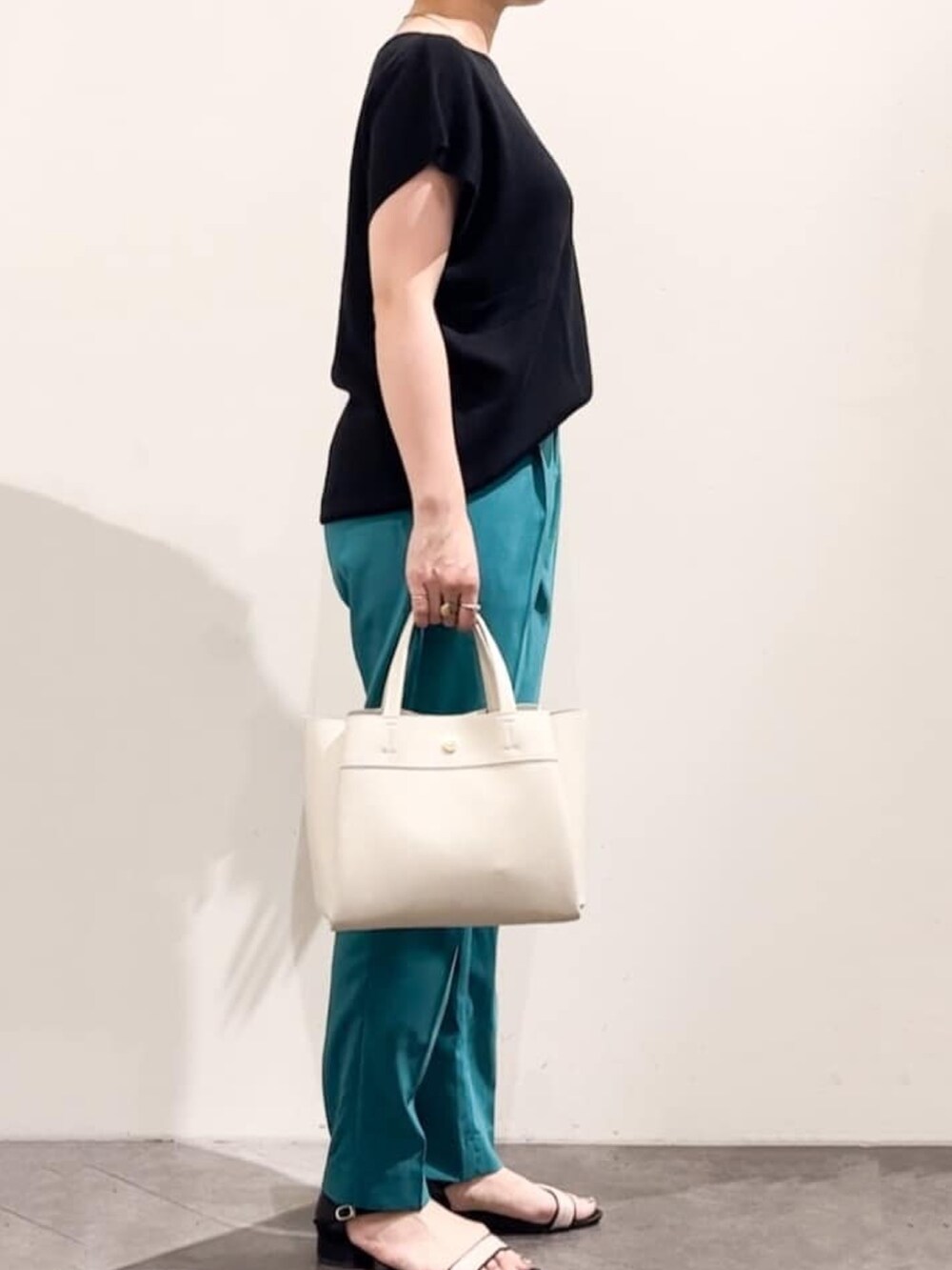 ブラック系のニット/セーター、グリーン系のその他パンツ、ホワイト系のトートバッグを着用したレディースの夏コーディネートの2枚目の写真