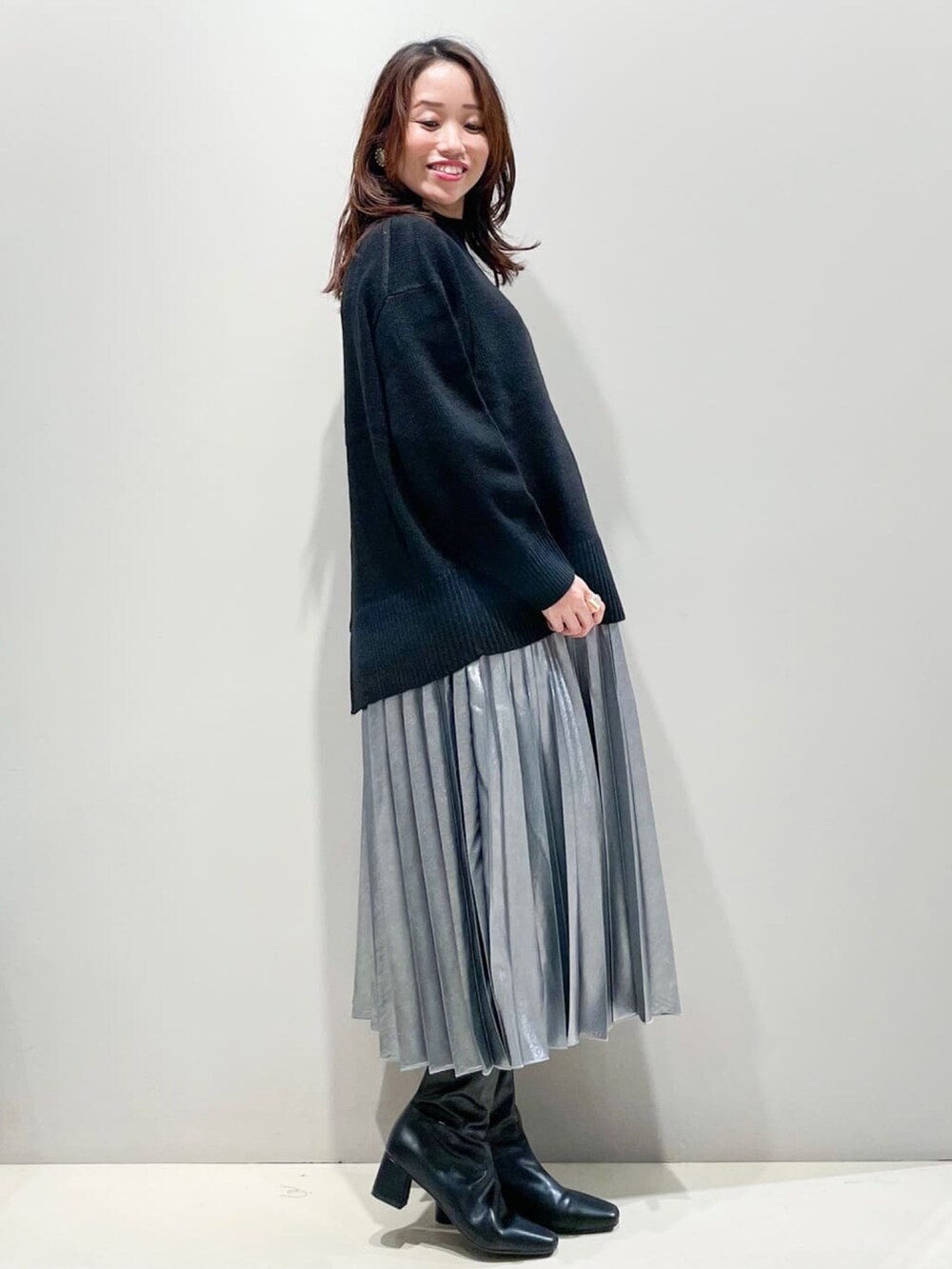 ブラック系のニット/セーター、ブラック系のスカート、ブラック系のショルダーバッグを着用したレディースの秋コーディネートの2枚目の写真