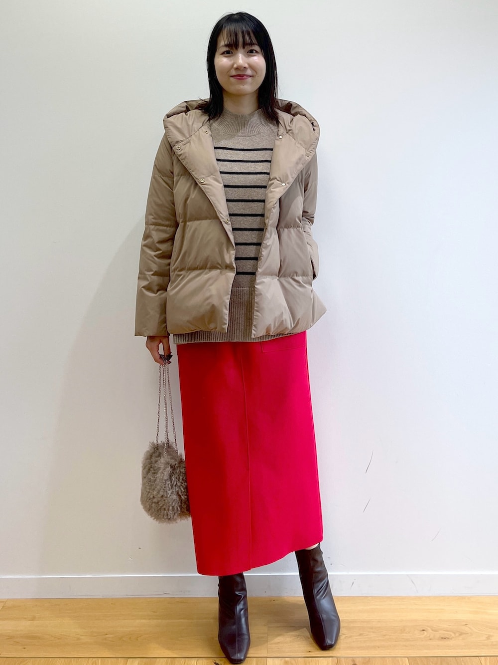 イエロー系のダウンジャケット/コート、ベージュ系のニット/セーター、レッド系のスカートを着用したレディースの秋コーディネートの2枚目の写真