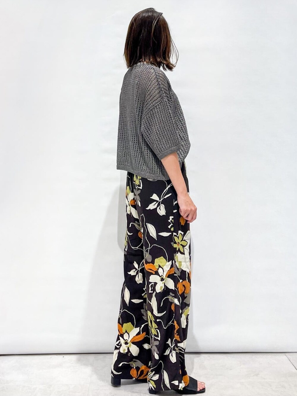 シルバー系のニット/セーター、ブラウン系のその他パンツ、ブラック系のショルダーバッグを着用したレディースの夏コーディネートの4枚目の写真