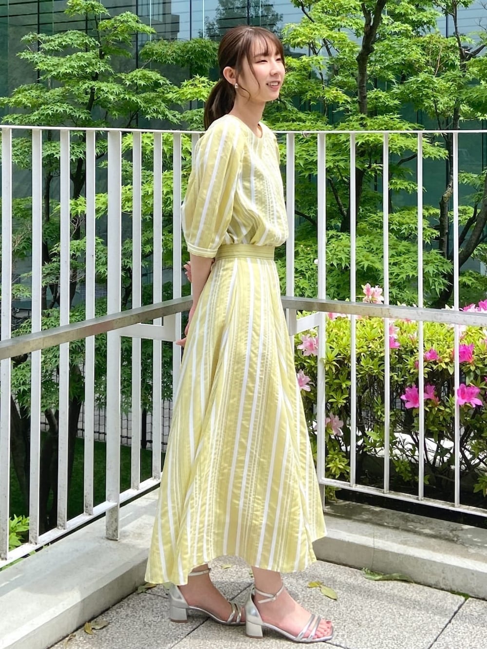 イエロー系のシャツ/ブラウス、イエロー系のスカート、シルバー系のサンダルを着用したレディースの春コーディネートの4枚目の写真
